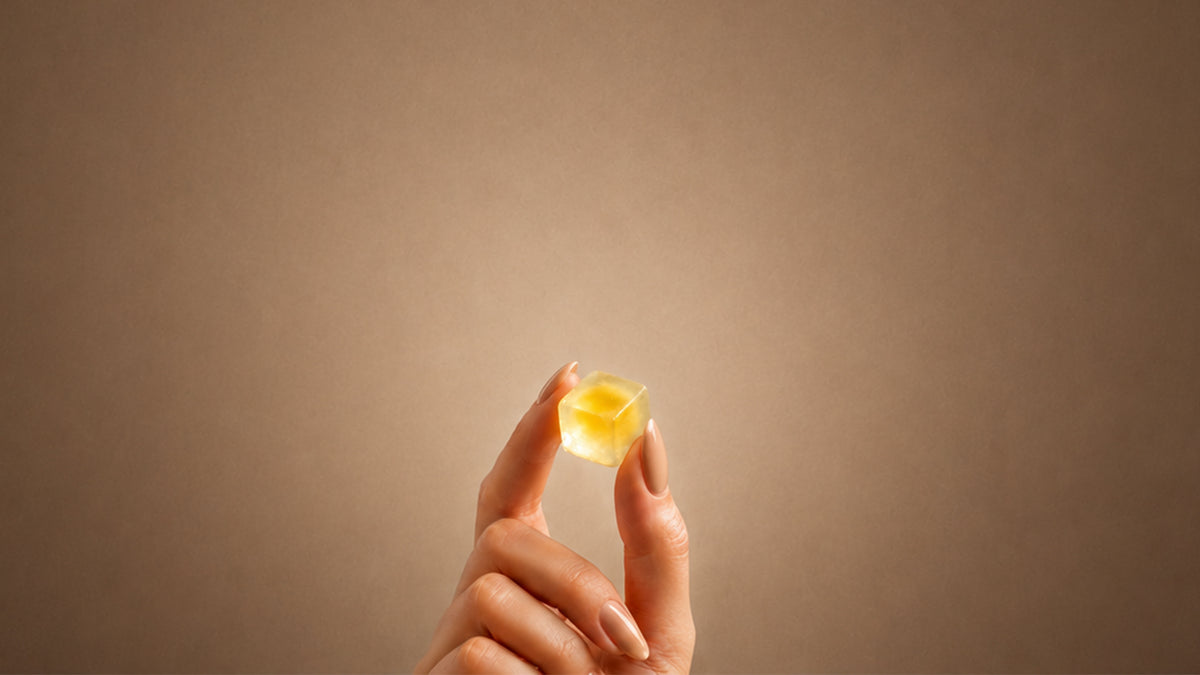 Eine Hand hält ein goldenes Fruchtgummi